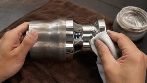 金属磨き剤と布で金属部品を磨き光沢を出す手元のアップ