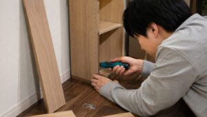 ペン型電動ドライバーで家具を組み立てる日本人男性