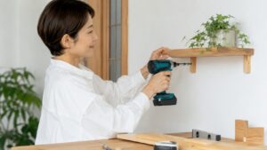 軽量ドリルドライバーで室内の木製棚を取り付ける日本人女性