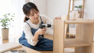 自宅で電動ドライバーを使い木製家具を組み立てる日本人女性