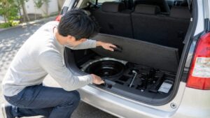 車のスペアタイヤと車載工具を確認する男性