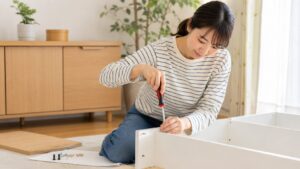 家庭用ドライバーで白い家具を組み立てる日本人女性
