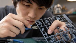 プラモデル用ニッパーでランナーから細かいパーツを切り出す日本人男性