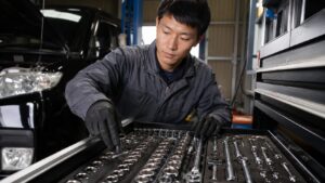 自動車整備士が工具チェストからソケットとラチェットを選ぶ様子