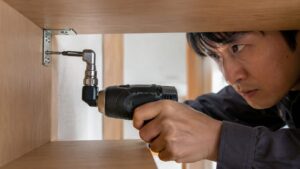 狭い棚の内側でL型アダプターを使いネジを締める日本人男性