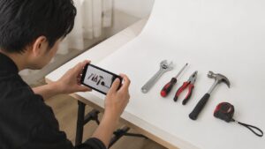 白背景に並べた工具をスマートフォンで撮影する様子