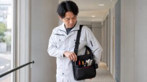 日本人作業者が工具ボディバッグからマーカーや小物工具を取り出す点検作業の様子