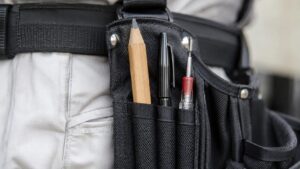 腰ベルトの工具ペンホルダーに鉛筆やペン、細軸ドライバーを差している close-up 画像