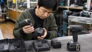 中古工具店でドリル本体とバッテリーや充電器の状態を確認する日本人男性