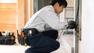 腰道具を装着して配線作業をする日本人電気工事士