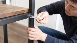 家具の六角ナットをサイズの合ったレンチで締める日本人男性のDIY作業